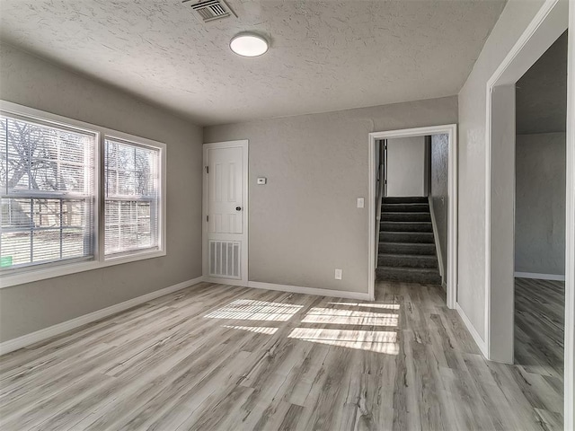 spare room with light hardwood / wood-style floors and a textured ceiling