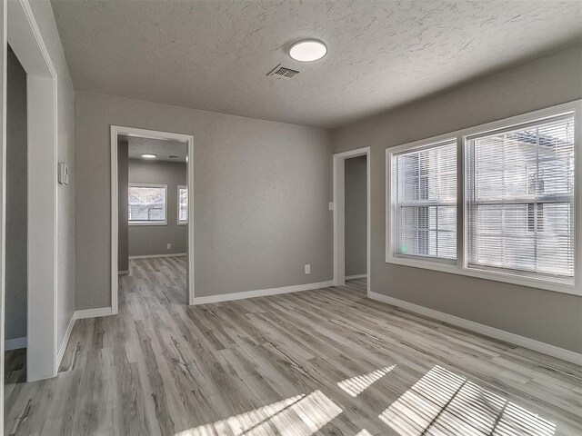 unfurnished room featuring light hardwood / wood-style flooring and a textured ceiling