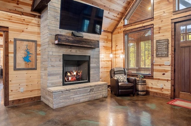 sitting room with a stone fireplace, wooden walls, and wooden ceiling