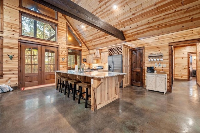 kitchen with wood walls, a kitchen island with sink, high vaulted ceiling, beam ceiling, and wood ceiling