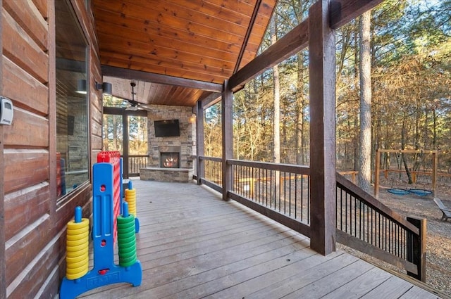 wooden deck with an outdoor stone fireplace and ceiling fan