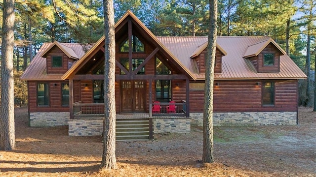 cabin with covered porch, metal roof, and faux log siding