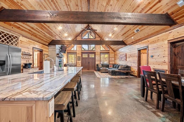 kitchen featuring a sink, open floor plan, stainless steel fridge, and wooden walls