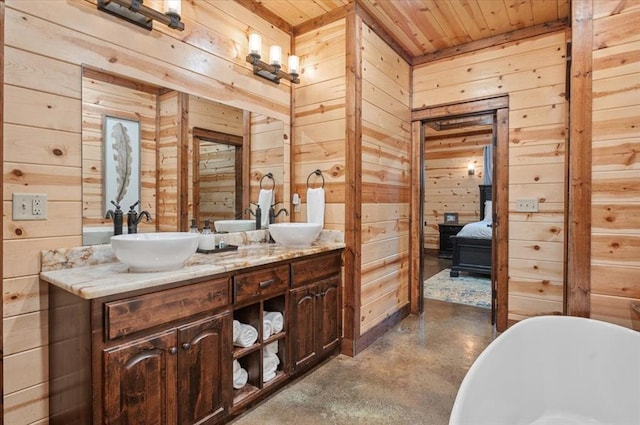 bathroom with finished concrete flooring, double vanity, a soaking tub, a sink, and wood walls