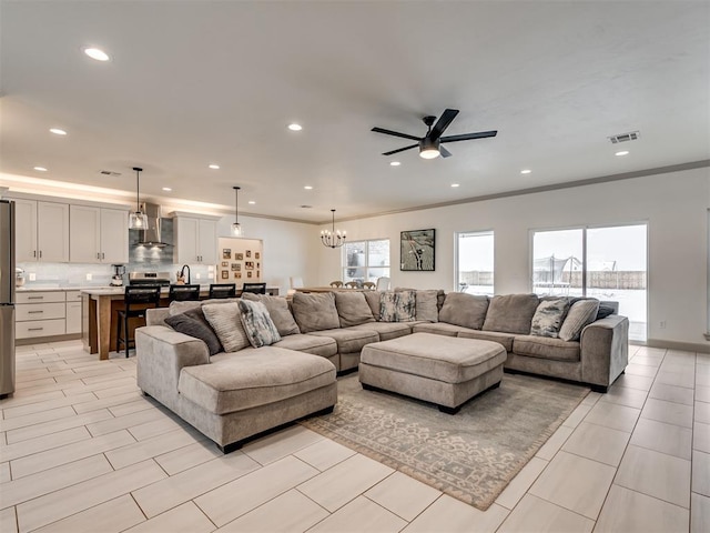 living room with ceiling fan with notable chandelier and ornamental molding