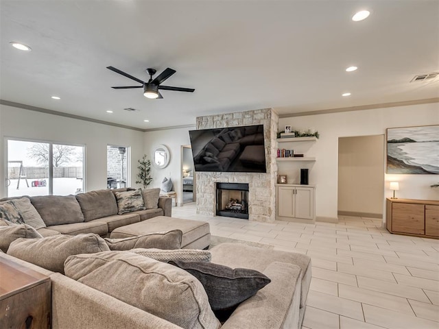 living room featuring ceiling fan, a stone fireplace, and crown molding