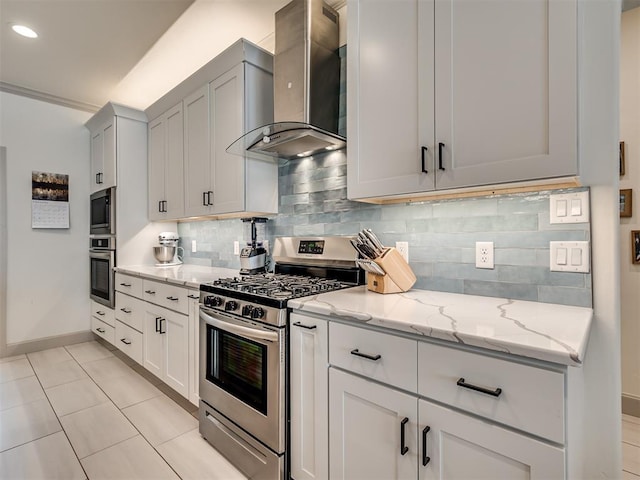 kitchen with light stone countertops, appliances with stainless steel finishes, wall chimney exhaust hood, decorative backsplash, and light tile patterned floors