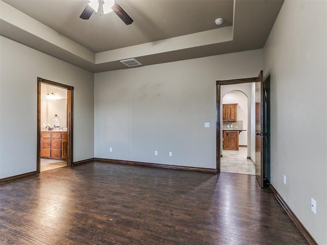 spare room featuring a tray ceiling, dark hardwood / wood-style floors, and ceiling fan