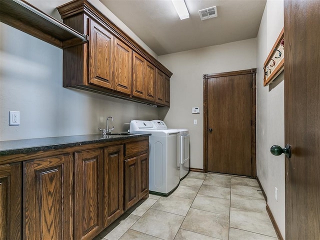 laundry area with cabinets, light tile patterned floors, washer and dryer, and sink