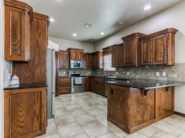 kitchen with backsplash, kitchen peninsula, a breakfast bar, and appliances with stainless steel finishes