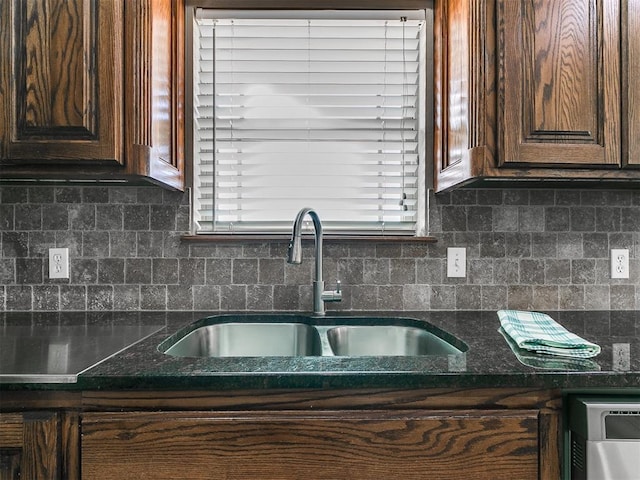 kitchen with backsplash, dark brown cabinetry, sink, and dark stone counters