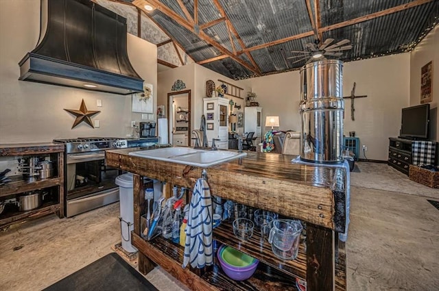 kitchen with high vaulted ceiling, sink, ceiling fan, stainless steel range, and custom range hood