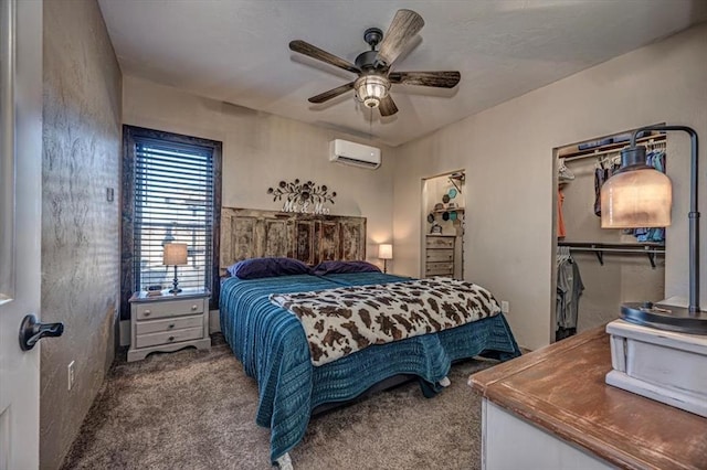 carpeted bedroom with a wall mounted AC, ceiling fan, a closet, and a walk in closet
