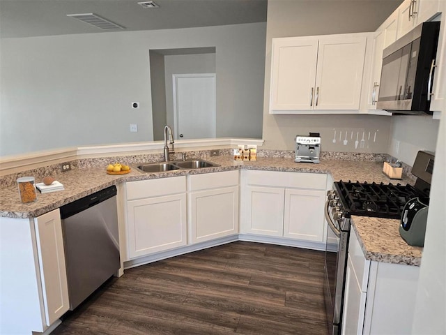 kitchen with white cabinetry, sink, stainless steel appliances, dark hardwood / wood-style floors, and kitchen peninsula