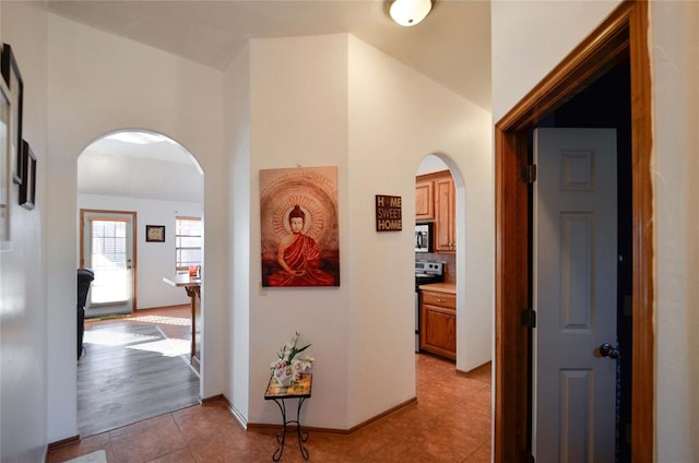 hallway with light tile patterned floors and vaulted ceiling