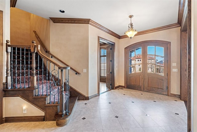 foyer entrance with french doors, crown molding, and a chandelier