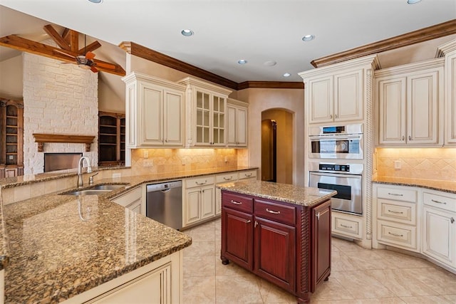 kitchen featuring ceiling fan, backsplash, a fireplace, stainless steel appliances, and cream cabinetry