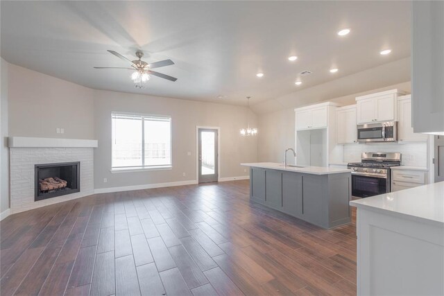 1300 Colonial Ave, Tuttle, OK 73089 - kitchen featuring appliances with stainless steel finishes, a kitchen island with sink, white cabinets, dark hardwood / wood-style flooring, and decorative light fixtures