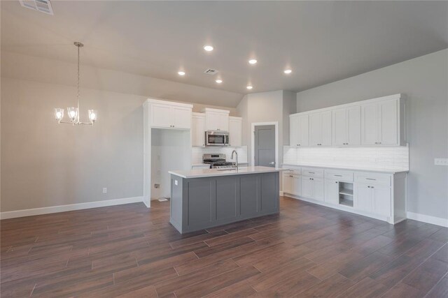 1300 Colonial Ave, Tuttle, OK 73089 - kitchen with dark wood-type flooring, white cabinetry, stainless steel appliances, an island with sink, and decorative light fixtures