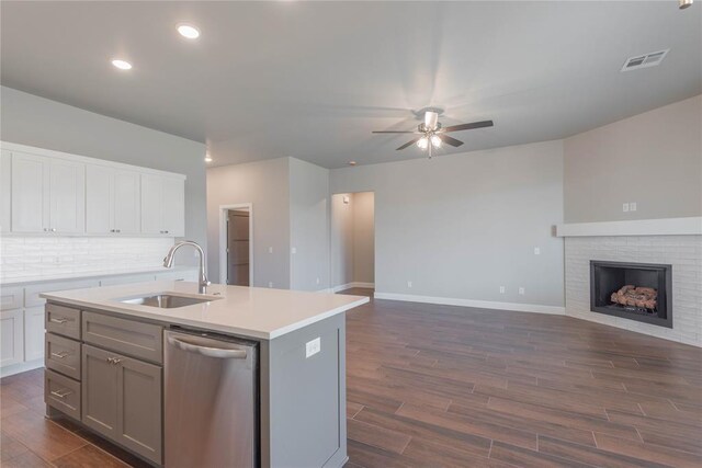 1300 Colonial Ave, Tuttle, OK 73089 - kitchen featuring sink, a brick fireplace, dark hardwood / wood-style flooring, dishwasher, and an island with sink