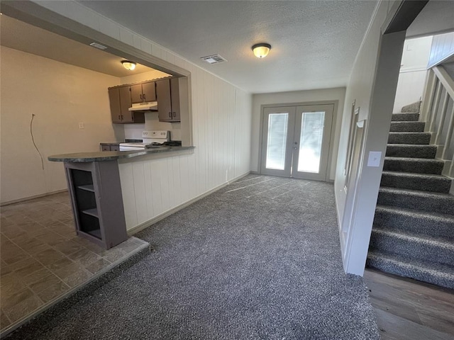 kitchen featuring kitchen peninsula, french doors, dark carpet, white electric range oven, and a textured ceiling