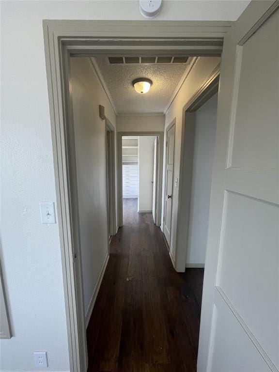 hall featuring ornamental molding, a textured ceiling, and dark wood-type flooring