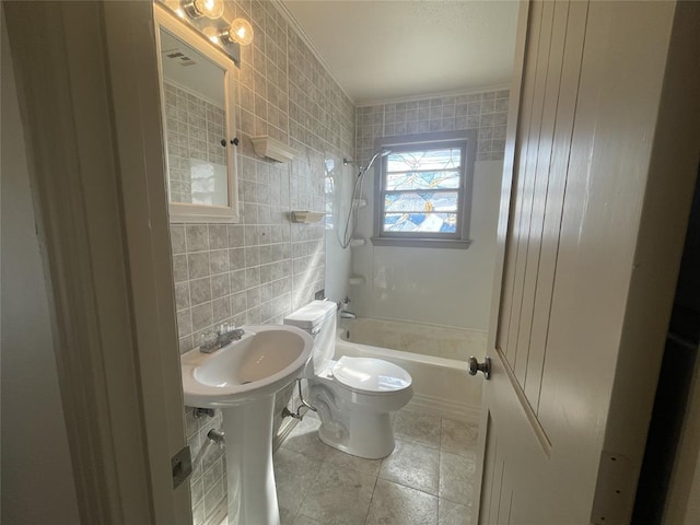 bathroom featuring toilet, shower / bath combination, and tile walls