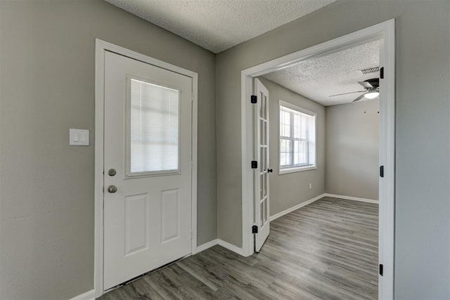 foyer entrance with ceiling fan, light hardwood / wood-style floors, and a textured ceiling