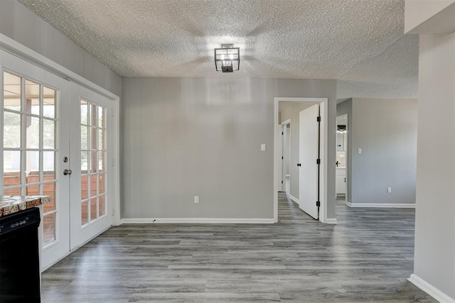 unfurnished dining area featuring french doors, a textured ceiling, and hardwood / wood-style flooring