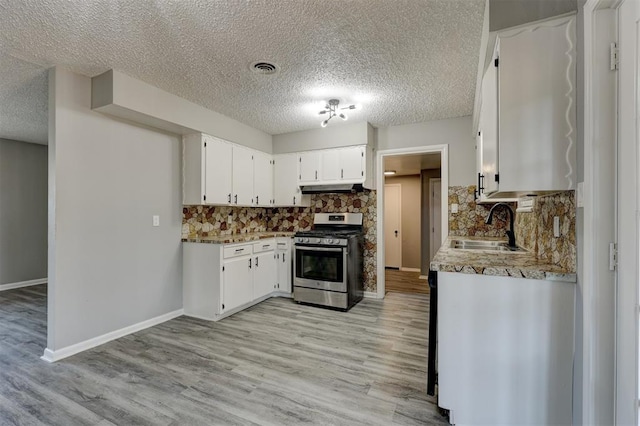 kitchen featuring sink, light hardwood / wood-style flooring, backsplash, white cabinets, and stainless steel range with gas stovetop