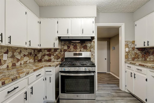 kitchen with stainless steel gas range oven, white cabinets, light stone countertops, tasteful backsplash, and extractor fan