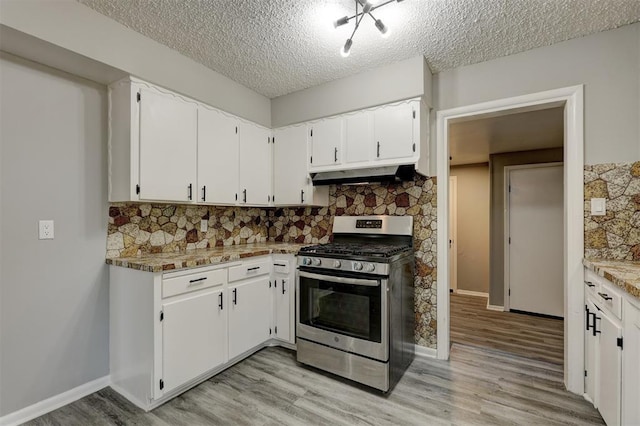 kitchen featuring gas stove, white cabinetry, light stone countertops, backsplash, and a textured ceiling