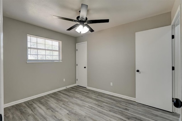 empty room with ceiling fan and light hardwood / wood-style flooring