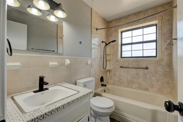 full bathroom with vanity, tiled shower / bath combo, toilet, and tile walls