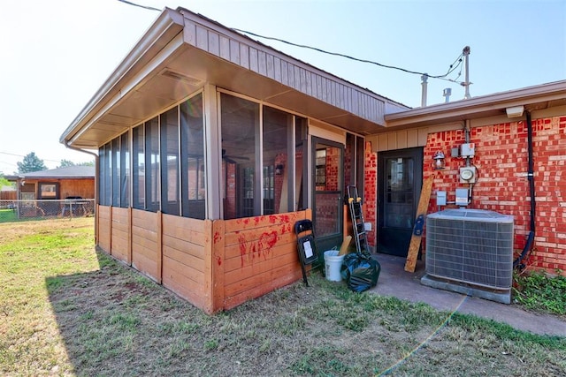 view of side of property with central AC, a lawn, and a sunroom