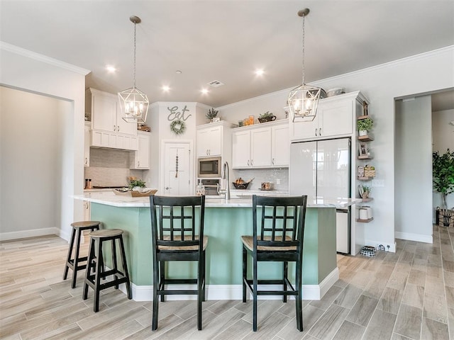 kitchen featuring white cabinetry, built in microwave, hanging light fixtures, a large island with sink, and a kitchen bar