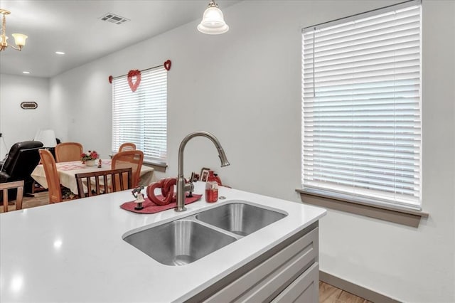 1305 Katelyn Ct, Yukon, OK 73099 - kitchen with light countertops, hanging light fixtures, a chandelier, and light wood finished floors