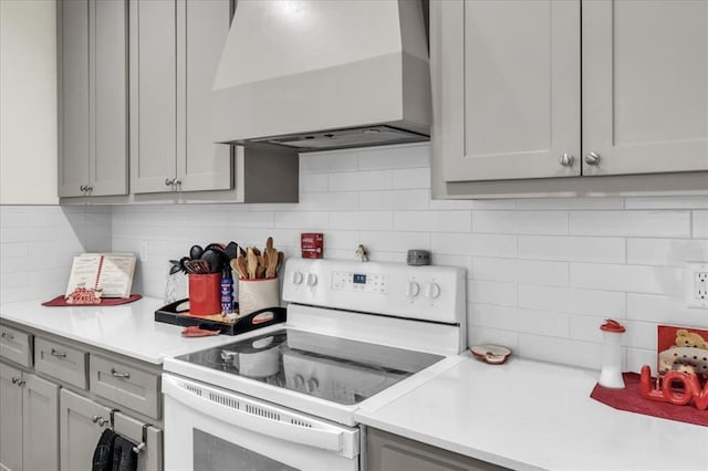 1305 Katelyn Ct, Yukon, OK 73099 - kitchen with white range with electric stovetop, wall chimney range hood, decorative backsplash, and gray cabinetry