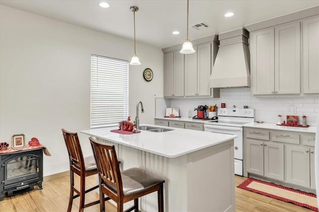 1305 Katelyn Ct, Yukon, OK 73099 - kitchen with electric stove, premium range hood, gray cabinetry, light wood-style flooring, and tasteful backsplash