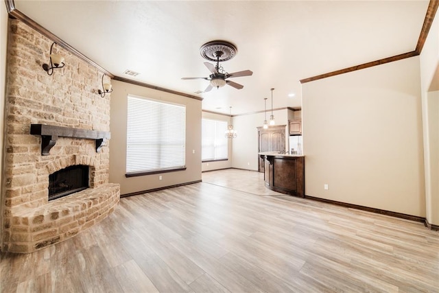 unfurnished living room with ceiling fan, light wood-type flooring, crown molding, and a fireplace