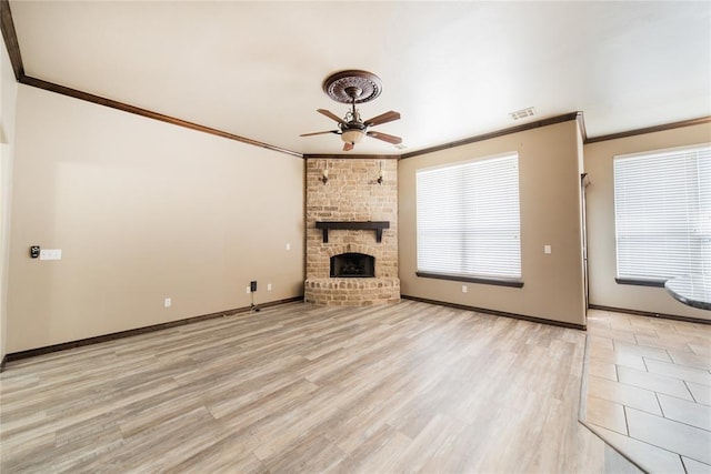 unfurnished living room featuring a brick fireplace, light wood-type flooring, ceiling fan, and crown molding