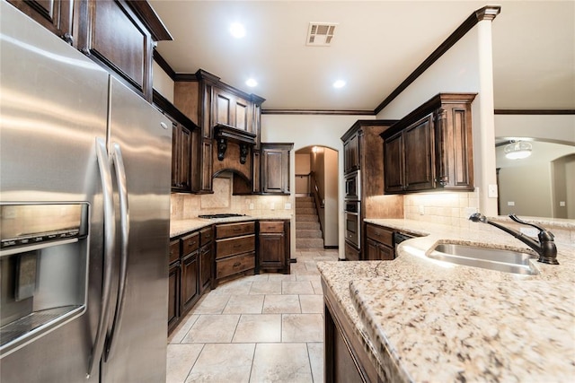 kitchen with appliances with stainless steel finishes, crown molding, dark brown cabinets, and sink