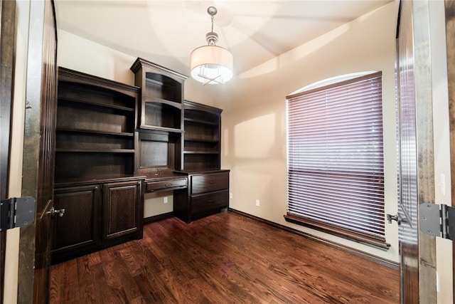 unfurnished office featuring built in desk, lofted ceiling, and dark hardwood / wood-style floors