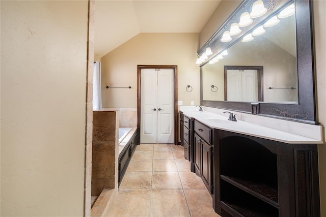 bathroom with lofted ceiling, tile patterned floors, a tub to relax in, and vanity