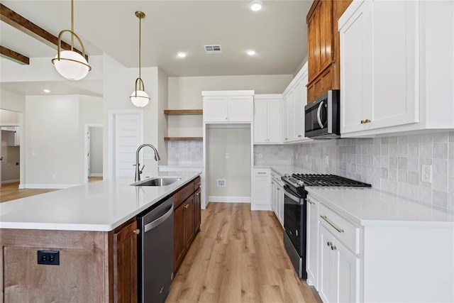 kitchen featuring pendant lighting, a center island with sink, sink, white cabinetry, and stainless steel appliances