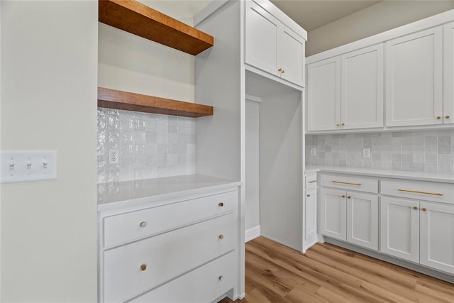 kitchen featuring white cabinets, decorative backsplash, and light wood-type flooring