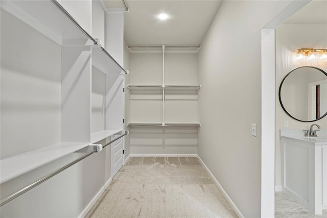 spacious closet featuring light colored carpet and sink