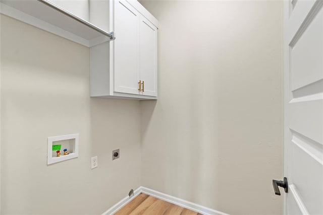 laundry room with hookup for an electric dryer, hookup for a washing machine, light hardwood / wood-style floors, and cabinets