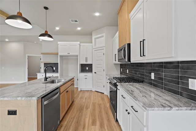 kitchen with decorative light fixtures, white cabinetry, stainless steel appliances, and an island with sink