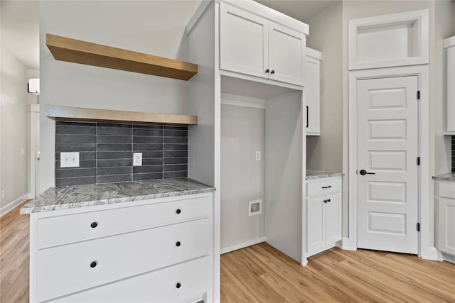 kitchen featuring decorative backsplash, white cabinets, light stone counters, and light wood-type flooring